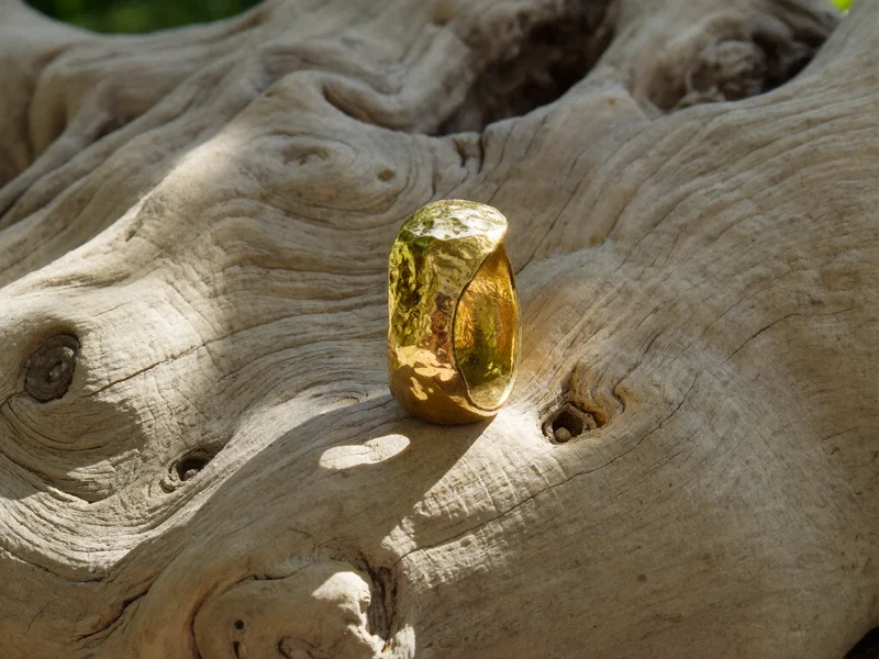 Bague en or martelée posée sur un morceau de bois flotté