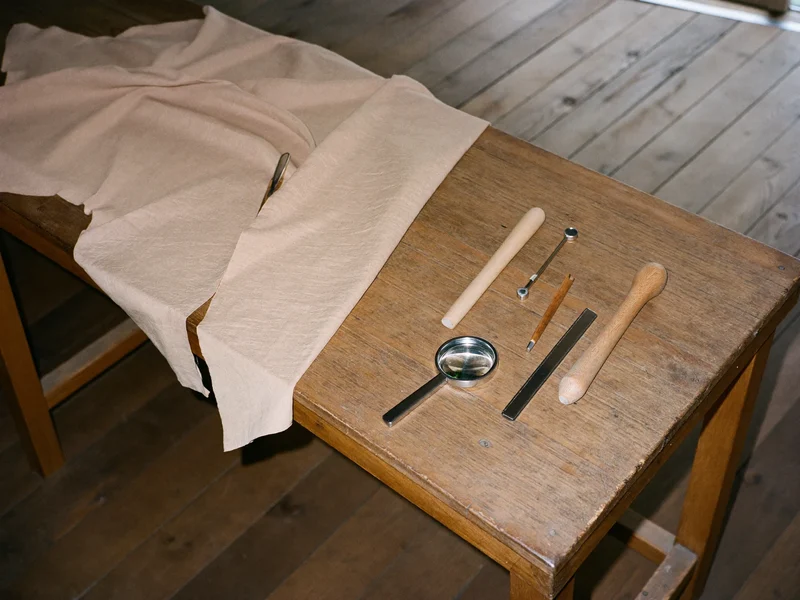 Établi de bijoutier avec outils simples, loupe et tissu, vu du dessus